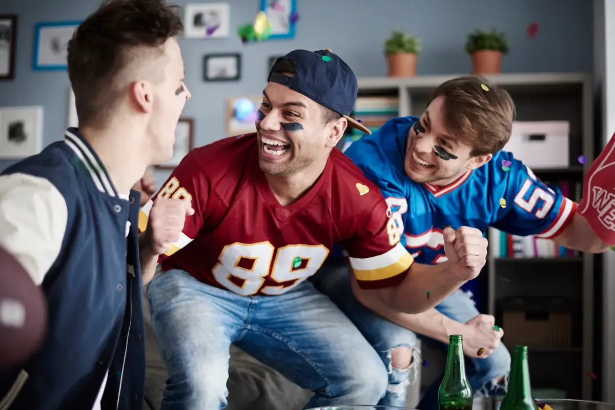 Fantasy sports advice with excited fans in jerseys celebrating a football game at home with confetti.