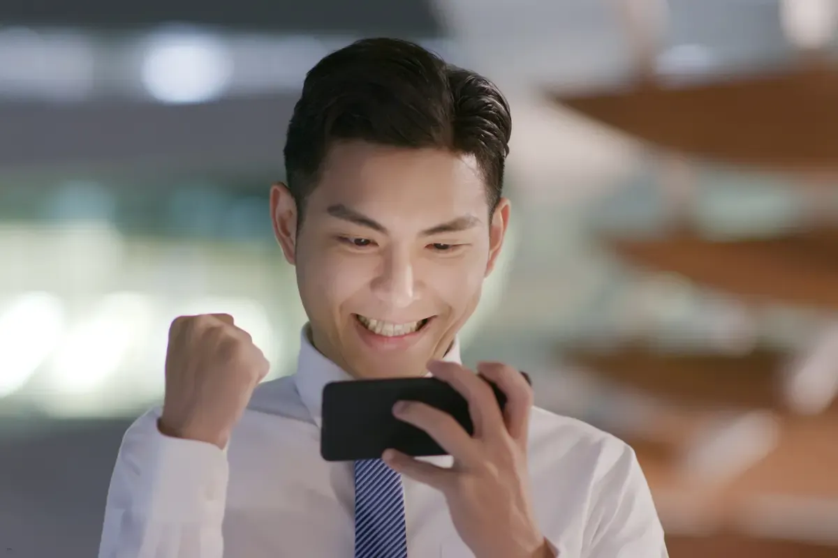 A man celebrating while watching his phone, representing success in daily fantasy betting