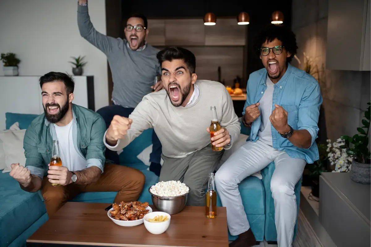 NFL daily fantasy fans cheering energetically with snacks and drinks during a game in a cozy living room