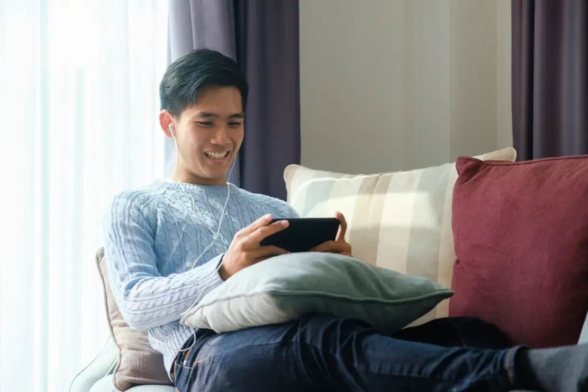 Daily fantasy sports fan watching game updates on a tablet while relaxing on a couch