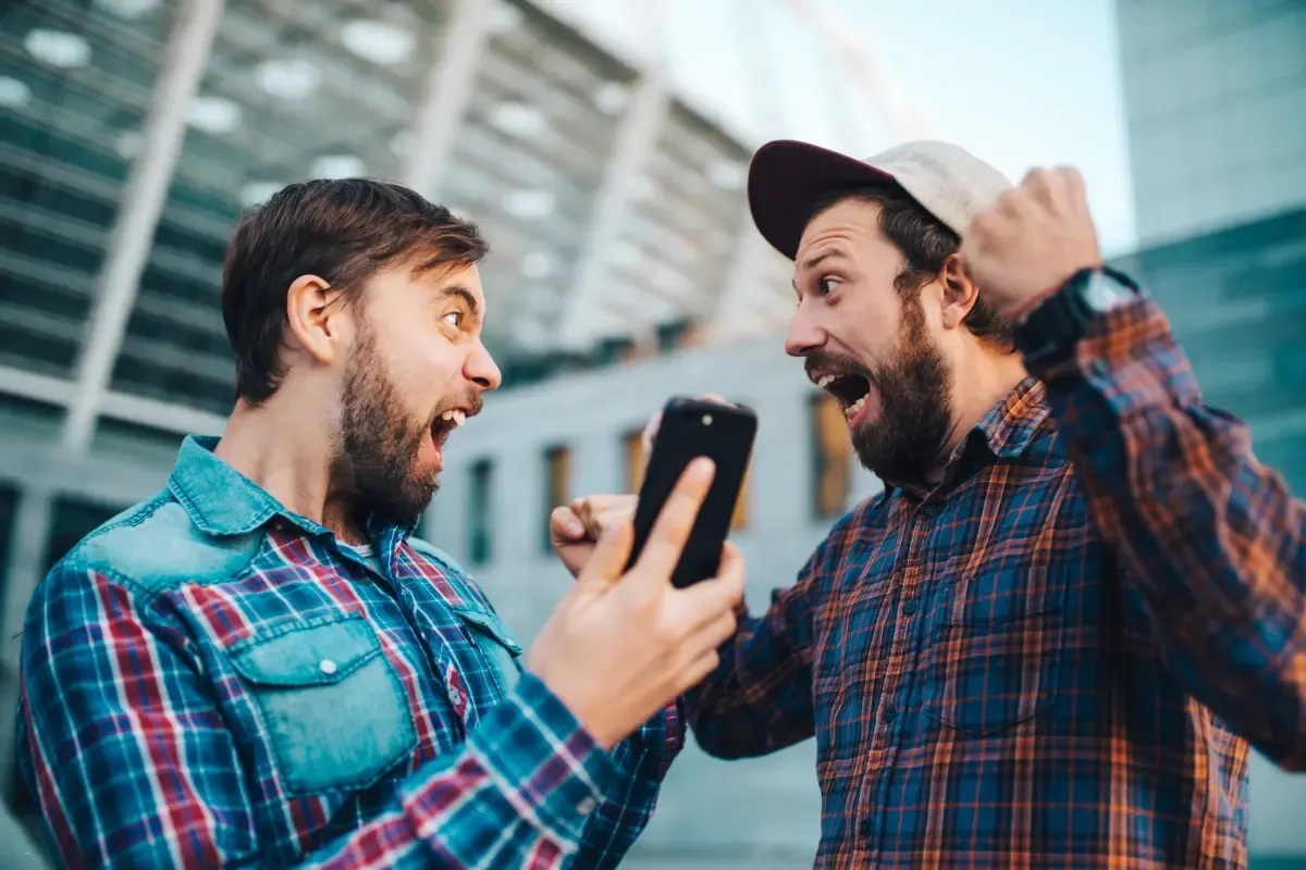 NFL survivor pool online fans cheering while looking at a smartphone outside a stadium