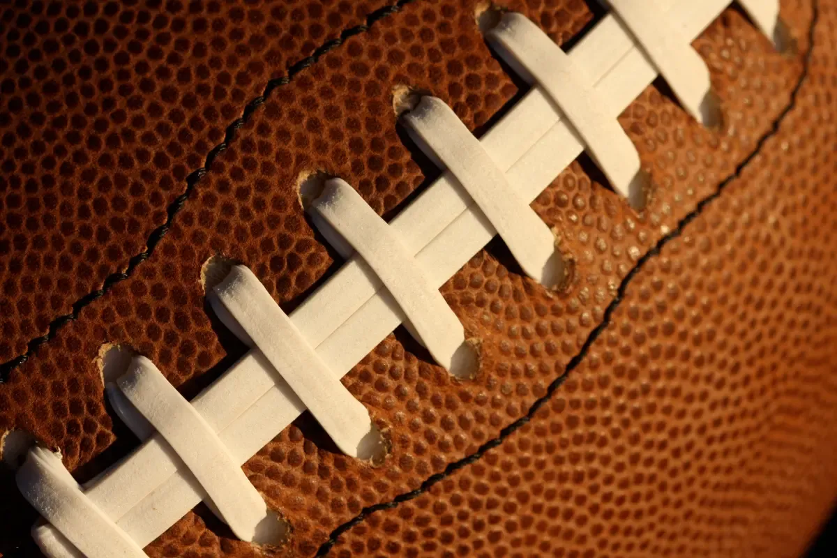 Strategies for NFL playoff picks close-up of a football's laces and texture illuminated in warm lightin