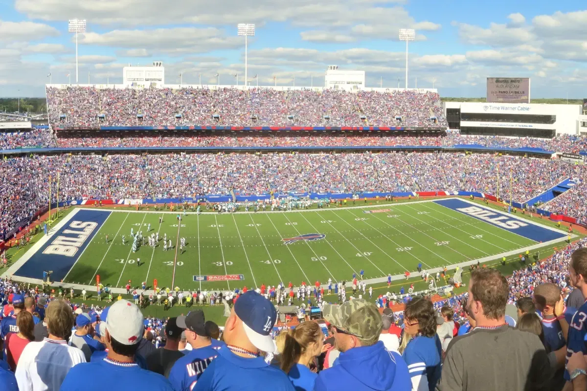 A packed football stadium with fans watching a live game under a bright blue sky