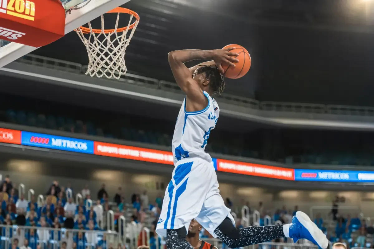NBA fantasy players as a basketball player soars through the air for a slam dunk during a game.