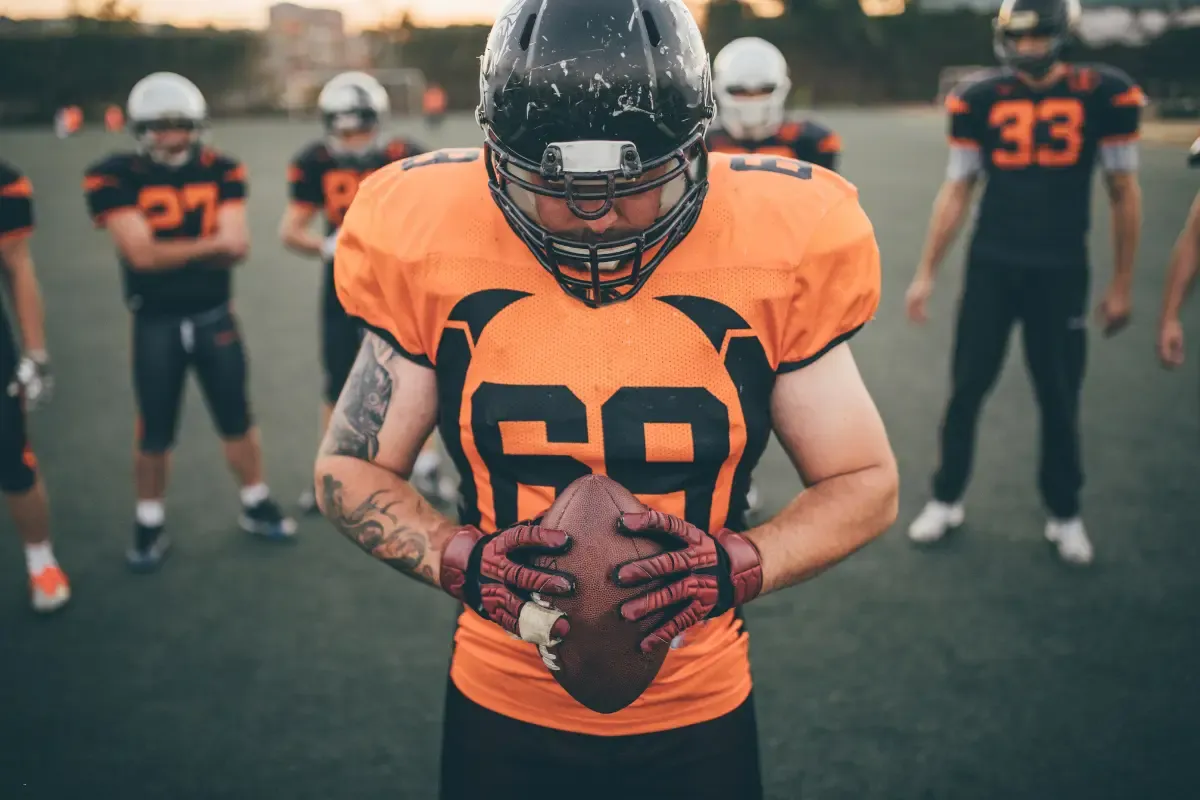 Weekly NFL survivor pools preparation with a football player holding the ball and teammates gathered on the field.