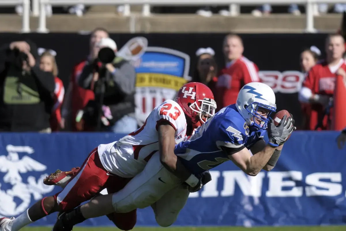 NFL survivor pool strategy captured in a dramatic tackle during a competitive college football game.