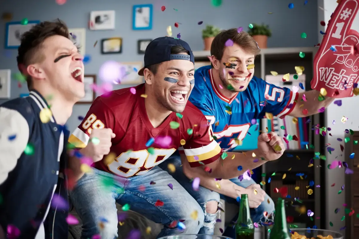 Risk management in NFL survivor pools visualized by excited fans watching a game at home surrounded by confetti.