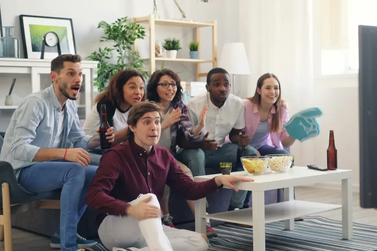 NFL survivor picks represented by a mixed group of fans intensely watching a football game on TV.