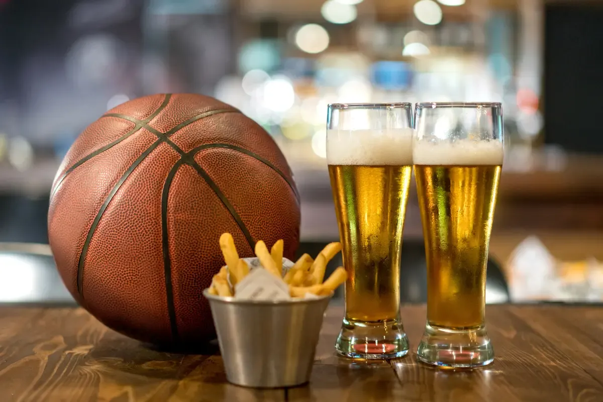Building fantasy rosters concept shown with beer, fries, and a basketball on a bar counter.