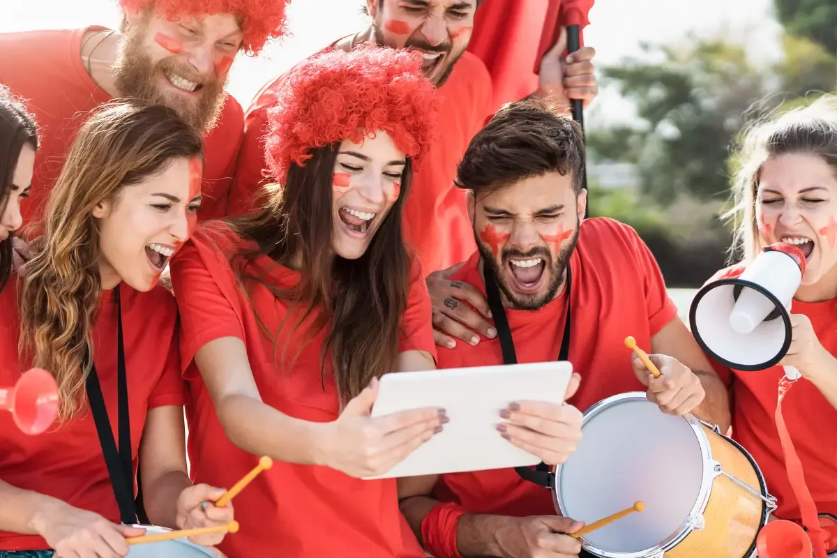 Weekly survivor picks shown as a group of fans in red cheer while watching game highlights on a tablet.