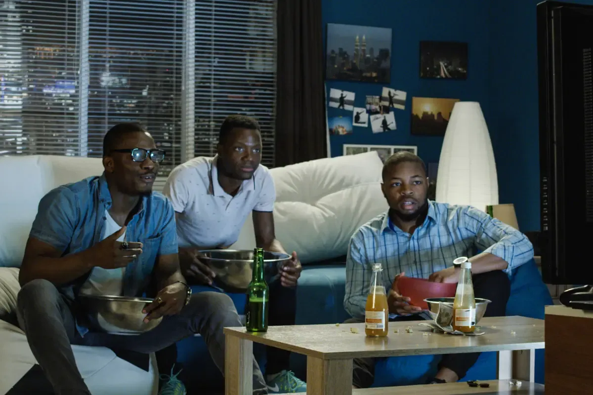 Tiers fantasy league experience captured by focused fans watching a game at night with snacks and drinks.