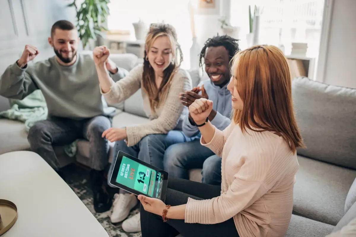Fantasy sports sites excitement as friends celebrate a win while watching results on a tablet