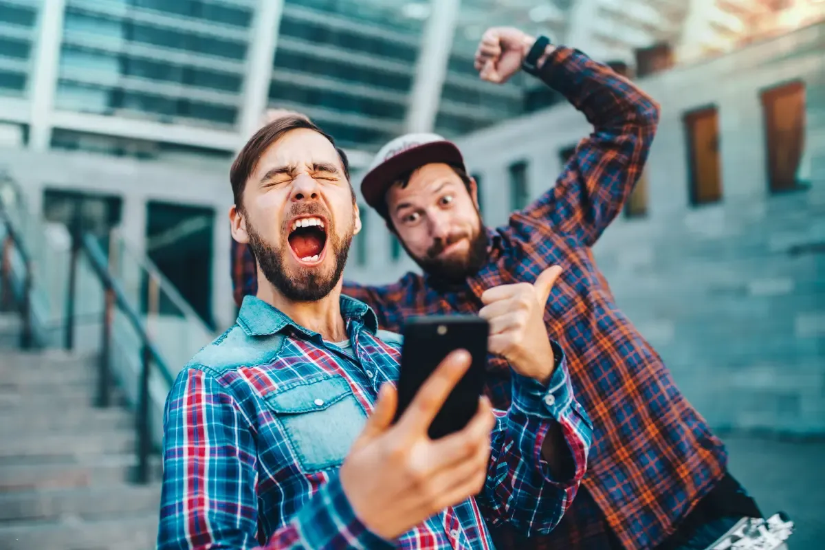 Fantasy sports platforms thrill as two men react joyfully to a mobile app score update outdoors