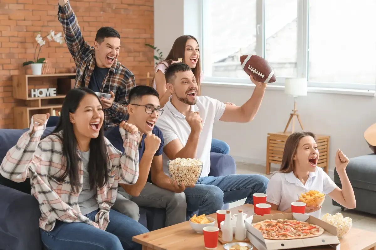 NFL fantasy picks celebration with a diverse group cheering during a game night with pizza and popcorn