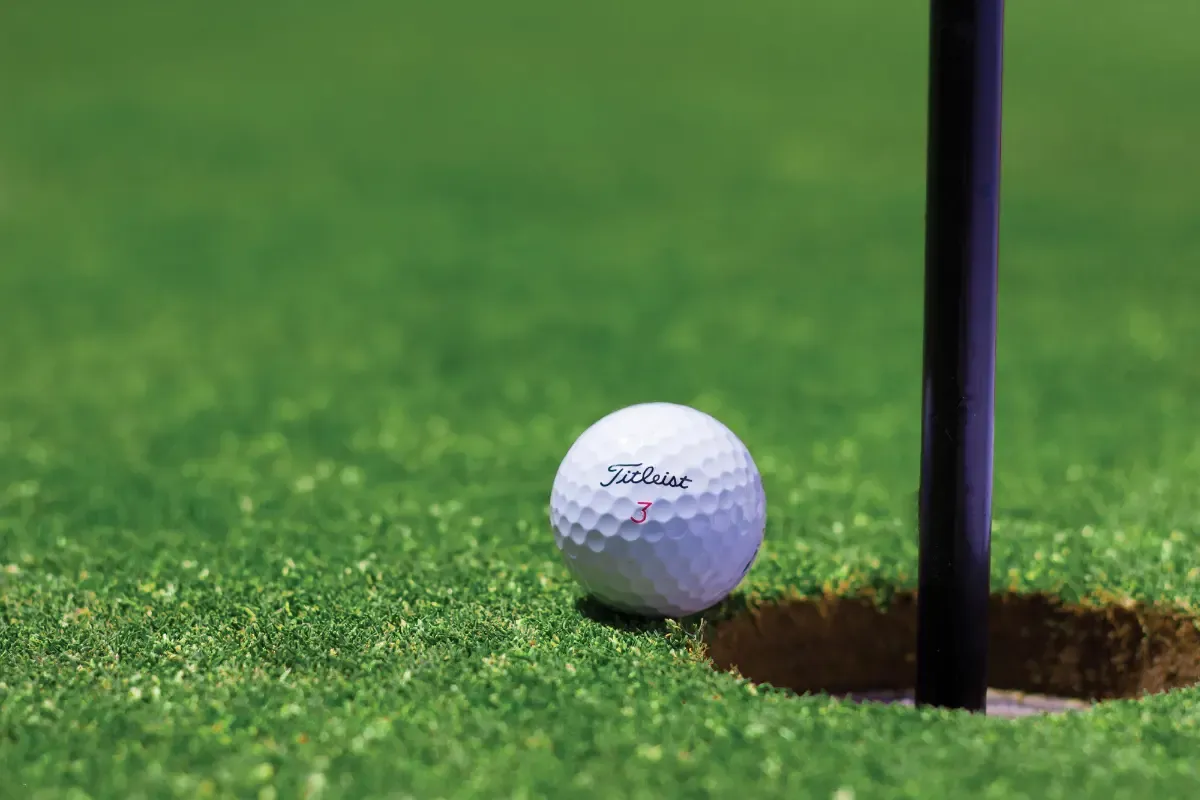 Fantasy golf strategy visual showing a Titleist golf ball near the hole on a putting green