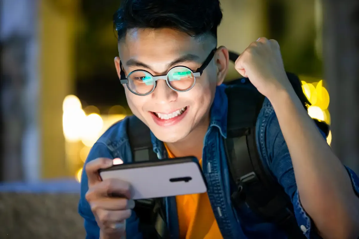 NFL moneyline picks excitement shown by young man cheering while watching phone screen at night.