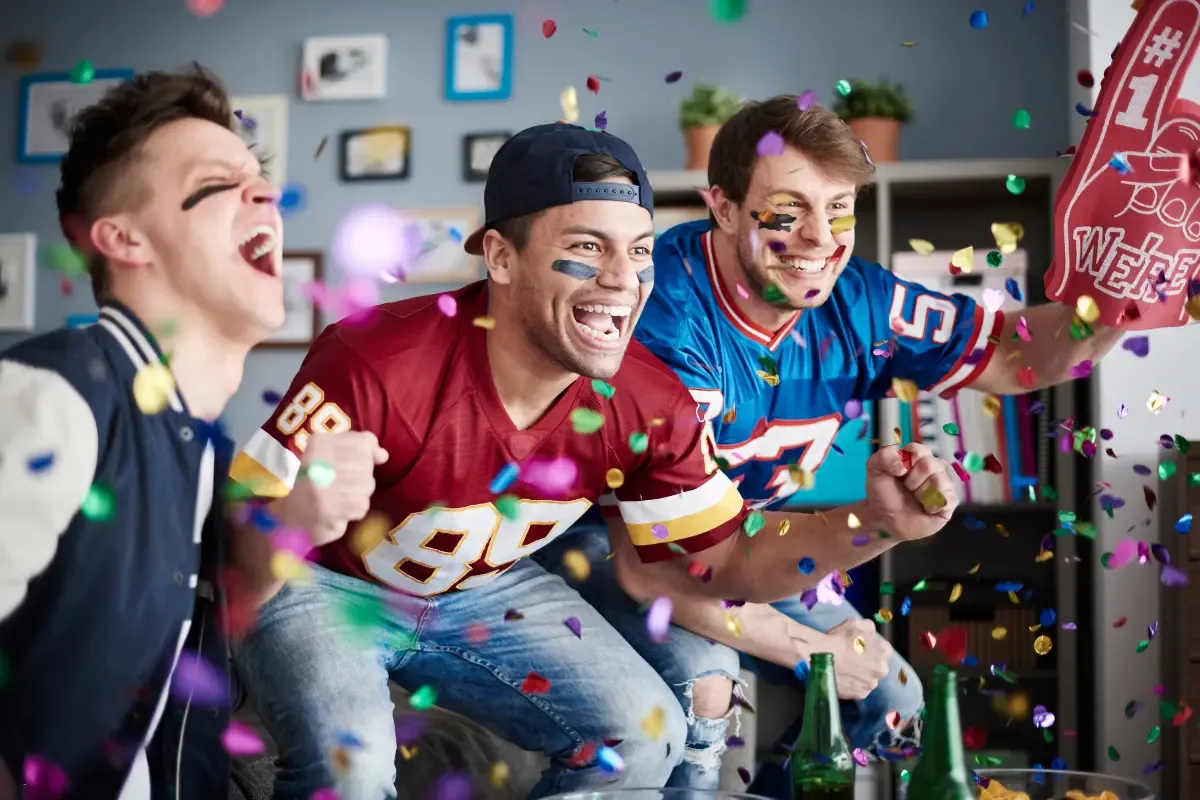 NFL fantasy survivor fans cheer energetically in football jerseys amid confetti and game excitement