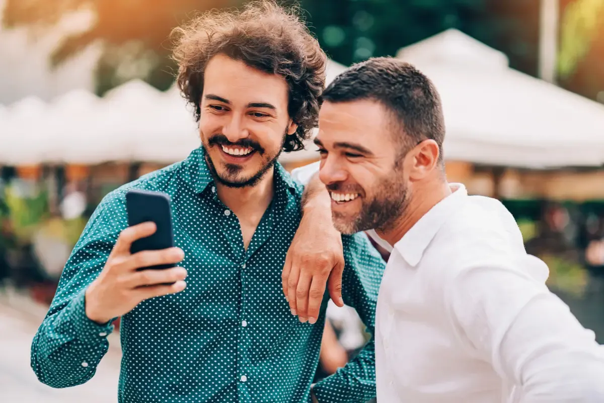 NFL office pools excitement as two colleagues smile while checking game results on a smartphone outdoors