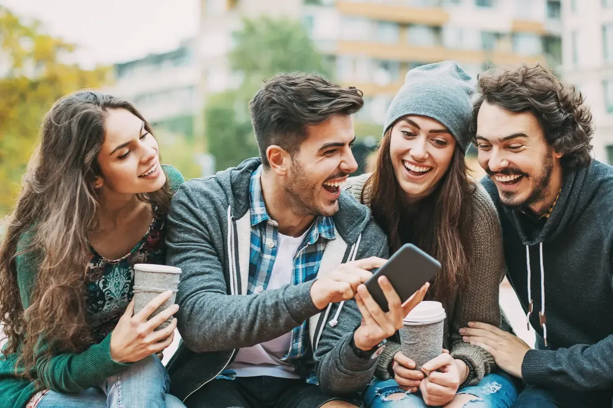 NFL survivor pool app being used by a group of friends excitedly viewing something on a smartphone outdoors