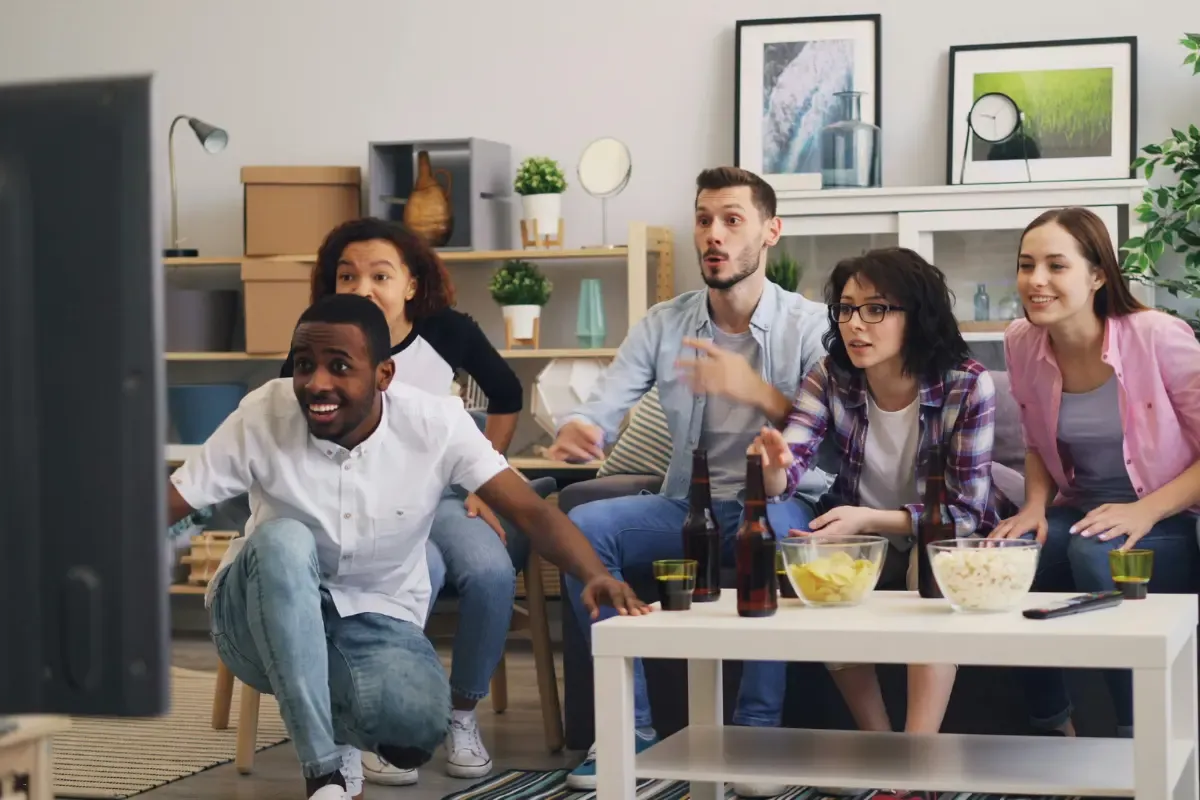 Fantasy football daily picks group intensely focused on a game broadcast while seated around snacks and drinks