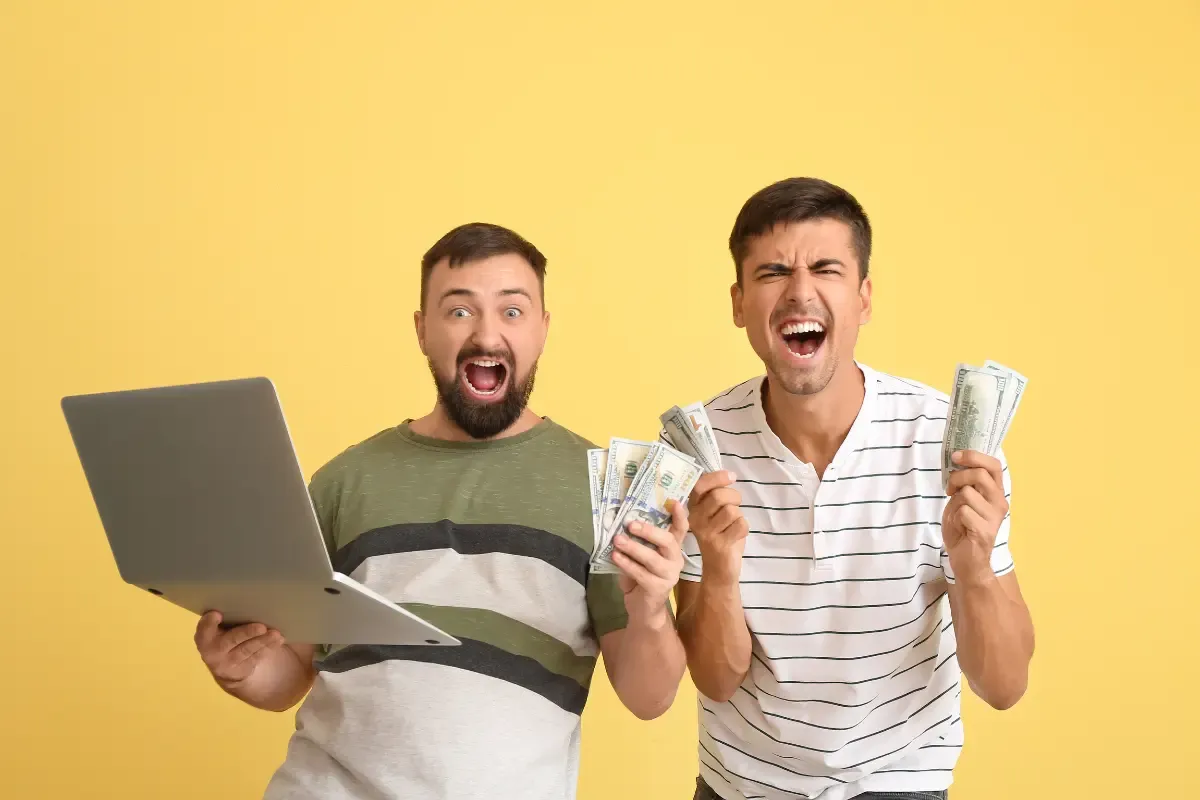 NFL elimination odds lead to huge win as two men celebrate holding cash and a laptop against a yellow background.