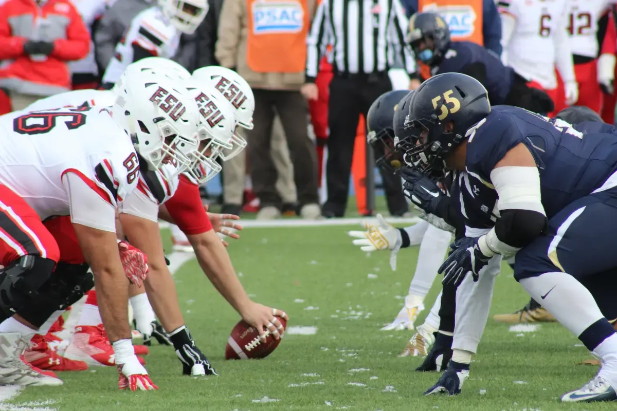 College football matchup with two opposing teams lined up at the line of scrimmage before the snap
