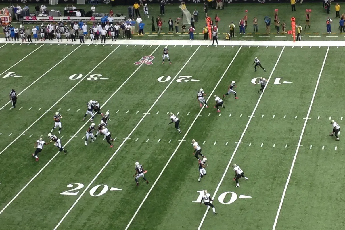 College football game action with players running a play on the field, viewed from above