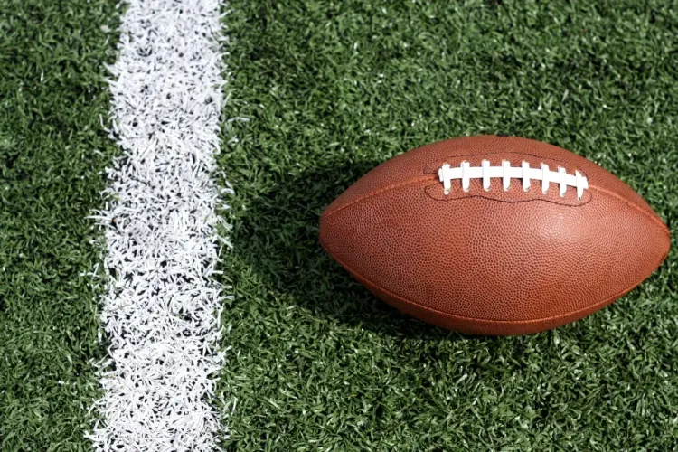 Football lying on a field next to a white line, ready for play