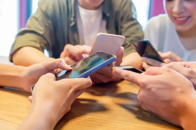 Daily fantasy sports online players using smartphones at a table, engaging with their screens in a social setting