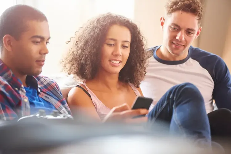 Daily fantasy sports players checking scores on a smartphone while sitting together on a couch.