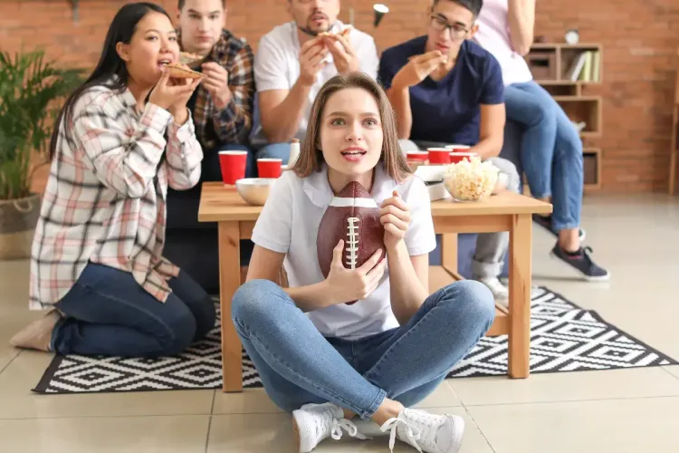 NFL survivor pool watch party with a group of friends enjoying snacks while a woman holds a football