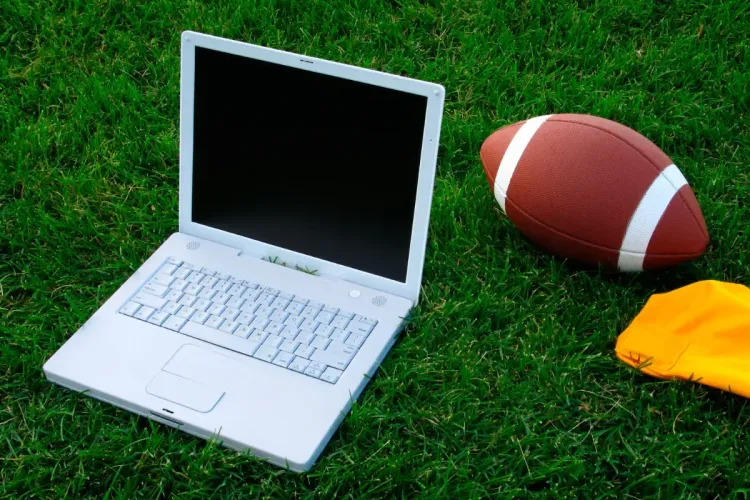 Football, laptop, and penalty flag resting on green grass