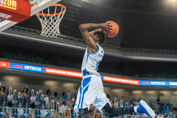 NBA fantasy players as a basketball player soars through the air for a slam dunk during a game.