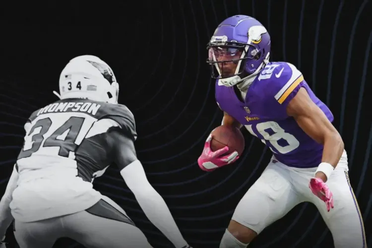 NFL wide receiver dodges defender during an intense play under stadium lights.